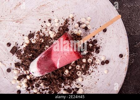 Popsicle di gelato alla fragola con panna montata decorata cioccolato su sfondo bianco di legno. Vista dall'alto Foto Stock