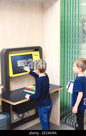 Ragazzi che utilizzano un punto self-service nella libreria Foto Stock