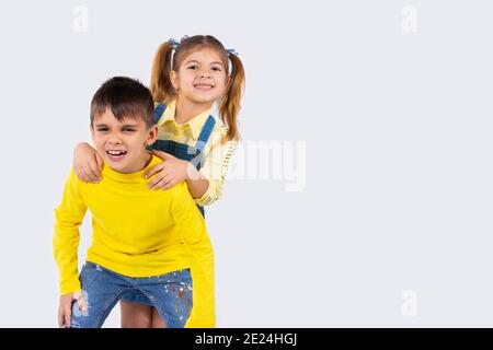 Bei bambini luminosi fanno i volti sorridenti e in posa su uno sfondo bianco con spazio laterale vuoto. Foto Stock