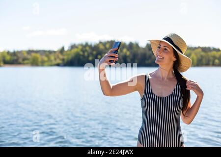 Donna che prende selfie al lago Foto Stock