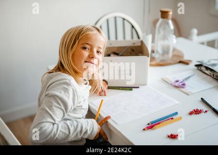 Sorridente ragazza a casa facendo i compiti Foto Stock