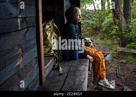 Ragazza con pug seduta da edificio in legno Foto Stock