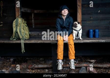 Ragazza con pug seduta da edificio in legno Foto Stock
