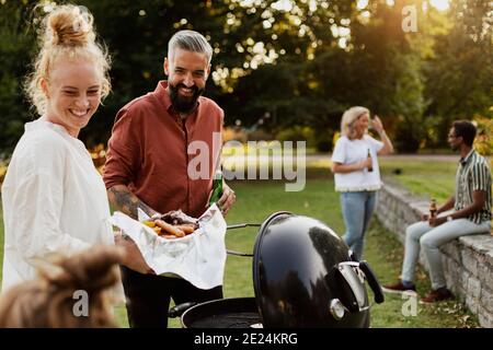 Amici che hanno barbecue nel parco Foto Stock