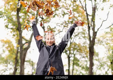 Giovane donna che lancia foglie d'autunno Foto Stock