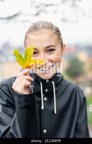 Ritratto di giovane donna che tiene foglia d'autunno Foto Stock