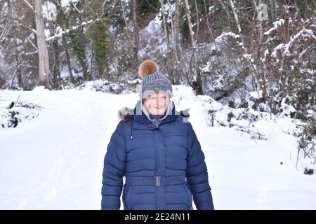 Donna anziana con giacca, cappello e faccia sorridente che si gode la neve. Scena dopo la tempesta di neve chiamata Filomena in Spagna. Gennaio 2021. Foto Stock