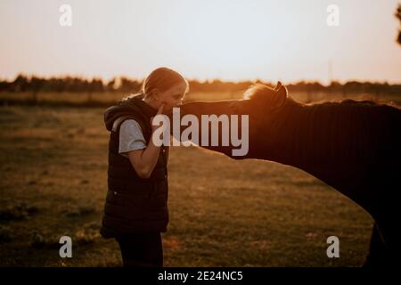 Ragazza con pony sul prato Foto Stock