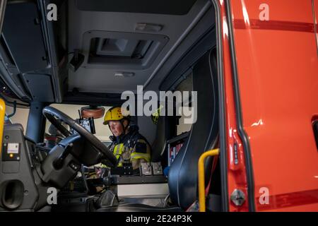 Firefighter femmina in seduta motore Fire Foto Stock