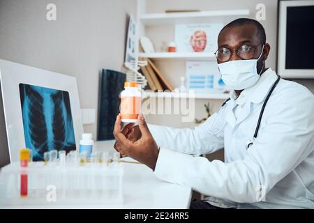 Pillole di pubblicità del medico di razza mista in bottiglia arancione Foto Stock