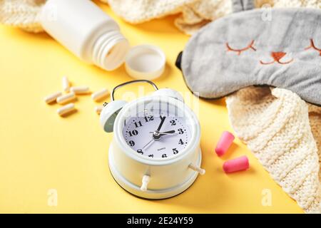 Maschera per il sonno, sveglia, tappi per le orecchie e pillole. Concetto creativo di sonno notturno sano. Buona notte, igiene del sonno, insonnia Foto Stock