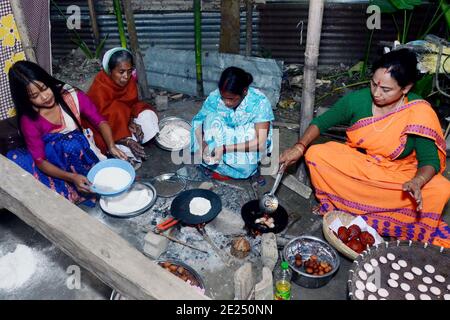 Nagaon, Assam, India - 12 gennaio 2021: Le donne del villaggio sono impegnate nella preparazione di pithas teel tradizionali e altri oggetti per Magh Bihu nel villaggio di Kachamari nel distretto di Nagaon di Assam, India. Magh Bihu, in particolare, è una celebrazione della generosità della messe della natura e un’ode alla continuità dell’esistenza. È naturale che Magh Bihu o Bhogali Bihu, come viene comunemente chiamato, sia una ricca celebrazione del ricco bacino di cibo tradizionale e di preparazioni gastronomiche dello Stato. Credit: Dita TALUKDAR/Alamy Live News. Foto Stock