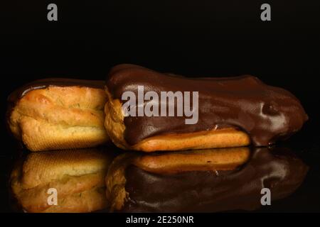 Due eclair al cioccolato, primo piano, su sfondo nero. Foto Stock