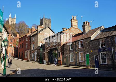 Strada principale acciottolata su una ripida collina con una fila di vecchie case e le torri della cattedrale sullo sfondo. Lincoln. Lincolnshire, Foto Stock