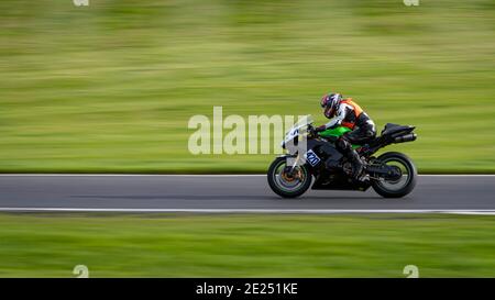 Un'inquadratura panoramica di una moto da corsa che si curva su una pista. Foto Stock