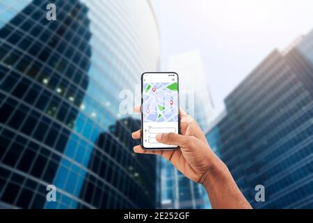 App di navigazione. Smartphone con applicazione GPS sullo schermo in mano nera maschio Foto Stock