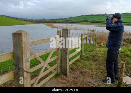 Birdwatcher guardando attraverso il suo binocolo a South Milton Ley Reserve. Thurlestone, South Devon, Regno Unito Foto Stock