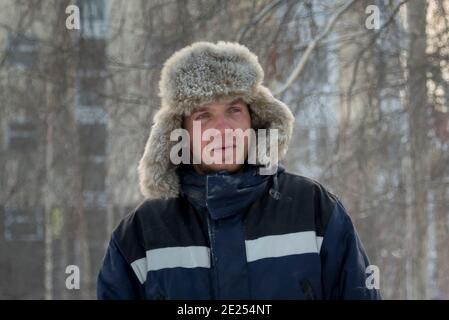 Ritratto di un uomo in un cappello con pelliccia leggera con una giacca invernale blu sul posto di lavoro Foto Stock