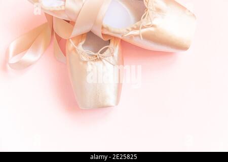 Nuove scarpe da ballo beige pastello con nastro in raso isolato su sfondo rosa. Ballerina scarpe classiche a punta per l'allenamento di danza. Scuola di balletto concep Foto Stock