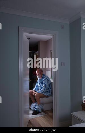 Un uomo anziano nel suo bagno in camera presto una mattina. Foto Stock