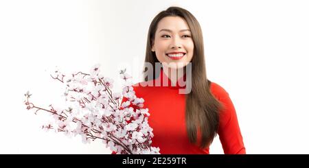 Felice sorridente giovane donna asiatica che tiene rami di pesca albero con fiori in fiore Foto Stock