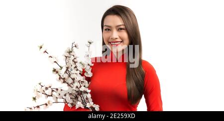 Belle donne asiatiche in rosso tradizionale abito vietnamita con tenuta ramo di fiori di pesca su sfondo bianco Foto Stock