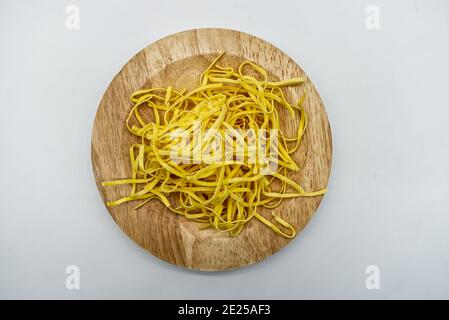 Tagliolini non cotti. Pasta fresca su ciotola di legno isolata su sfondo bianco. Foto Stock