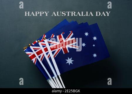 closeup di alcune bandiere australiane e il testo happy australia giorno su sfondo verde scuro Foto Stock