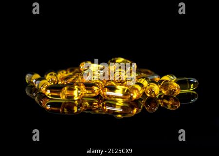 Capsule di olio di pesce su sfondo nero. Tema della salute. Foto Stock
