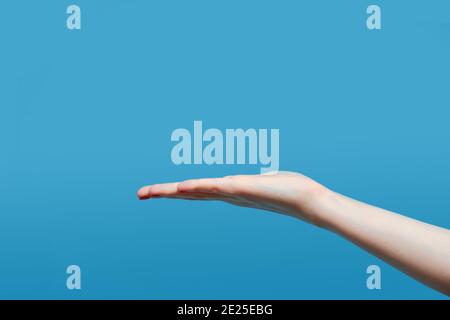 Primo piano della bella mano della donna isolata su sfondo blu. Spazio per la copia e il palmo Foto Stock