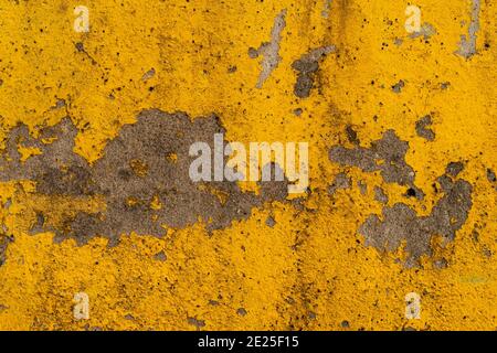 Vista ravvicinata della vernice giallo brillante che si stacca e si indossa su una superficie di cemento. Foto Stock