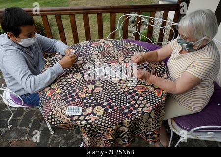 Carte da gioco adolescente con la nonna durante la pandemia. Eure, Francia. Foto Stock