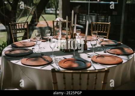 Tavolo con tovaglia bianca, piatti in legno e candele Foto Stock