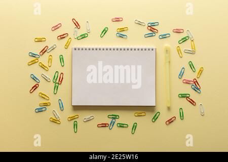 Aprire il blocco note a spirale su sfondo giallo , il notebook e la penna  si trovano su carta di tessuto, graffette di diversi colori Foto stock -  Alamy