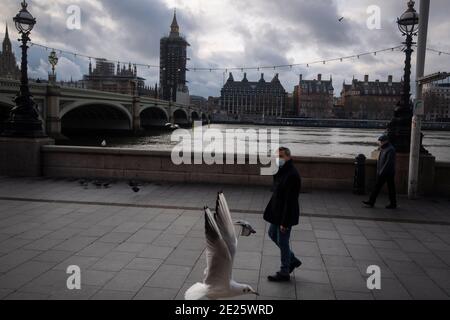 Un uomo che indossa un facemask cammina lungo la South Bank vicino a Westminster Bridge nel centro di Londra, mentre continua il terzo blocco nazionale dell'Inghilterra per frenare la diffusione del coronavirus. Foto Stock