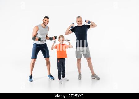 ragazzo felice con nonno e papà che si allenano con i manubri bianco Foto Stock