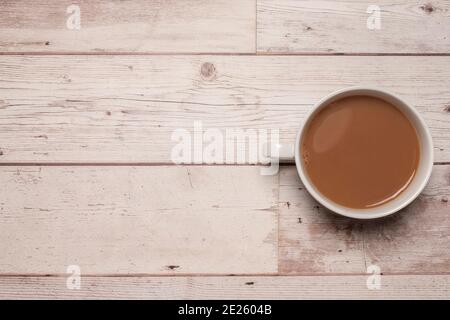 Tazza di tè o caffè forte con latte in una tazza bianca su una superficie testurizzata di legno bianco con spazio per la copia e spazio per il testo. Foto Stock