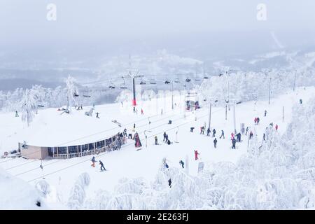 Perm Krai, Russia - 02 gennaio 2021: Stazione finale dello skilift e molti sciatori in cima alla montagna Foto Stock