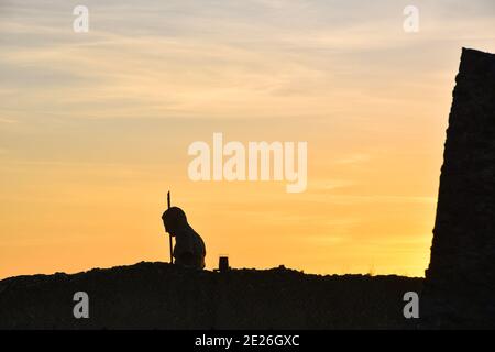 Vista delle rovine di Pompei al tramonto con la silhouette della statua dell'uomo e le mura distrutte. Concetto astratto vita tempo di morte. Italia attrazioni turistiche background Foto Stock