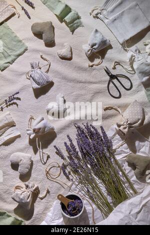 Sacchetti di lavanda fatti a mano in sacchetti di tessuto, cuori morbidi. Sacchetto per la presa a mano. Fiori secchi di lavanda per ripieno. Disposizione piatta, vista dall'alto, tovaglia tessile Foto Stock