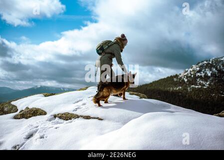 Ragazza giovane che guida un cane attraverso la neve nel montagne in inverno Foto Stock