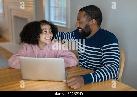 Un padre afroamericano e una figlia di Tween sorridono l'un l'altro Foto Stock