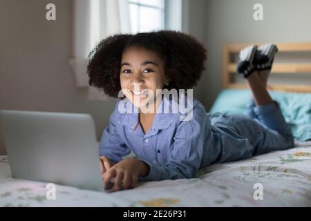 Dieci anni bisrazziale ragazza che lavora su Apple laptop sorridendo a. fotocamera Foto Stock
