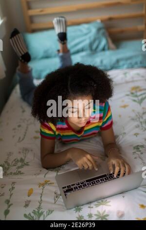 Vista dall'alto di una ragazza birazziale di dieci anni che lavora computer portatile Foto Stock