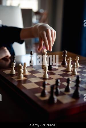 Primo piano della mano del bambino circa per spostare un pezzo in un gioco di scacchi. Foto Stock