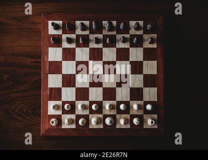 Vista dall'alto della scacchiera in legno e dei pezzi su un tavolo. Foto Stock