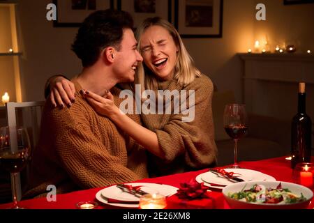 Felice giovane coppia agguantata ridendo festeggiando San Valentino insieme a casa. Foto Stock