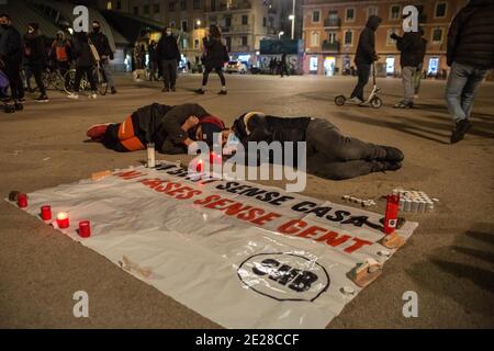 Barcellona, Catalogna, Spagna. 12 gennaio 2021. Due uomini sono visti sdraiati a terra per rendere omaggio ai senzatetto che sono morti dal freddo di fronte a un segno che dice, nessuna gente senza una casa, nessuna casa senza persone.l'Unione degli alloggi, da Barceloneta, un quartiere di Barcellona, Hanno convocato un raduno per due residenti del quartiere che hanno vissuto per strada e sono stati vittime fatali dell'ondata di freddo che infastidisce la Spagna. I manifestanti hanno reso omaggio alle vittime e hanno richiesto una dimora dignitosa per tutte le persone che vivono per strada. Credit: Thiago Prudencio/DAX/ZUMA Wire/Alamy Live News Foto Stock