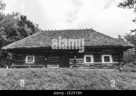 Foto in bianco nero della vecchia architettura rurale. Casa di legno con tetto in paglia, cabina di legno. Foto Stock