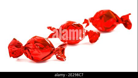 Tre caramelle rosse avvolte isolate su uno sfondo bianco Foto Stock